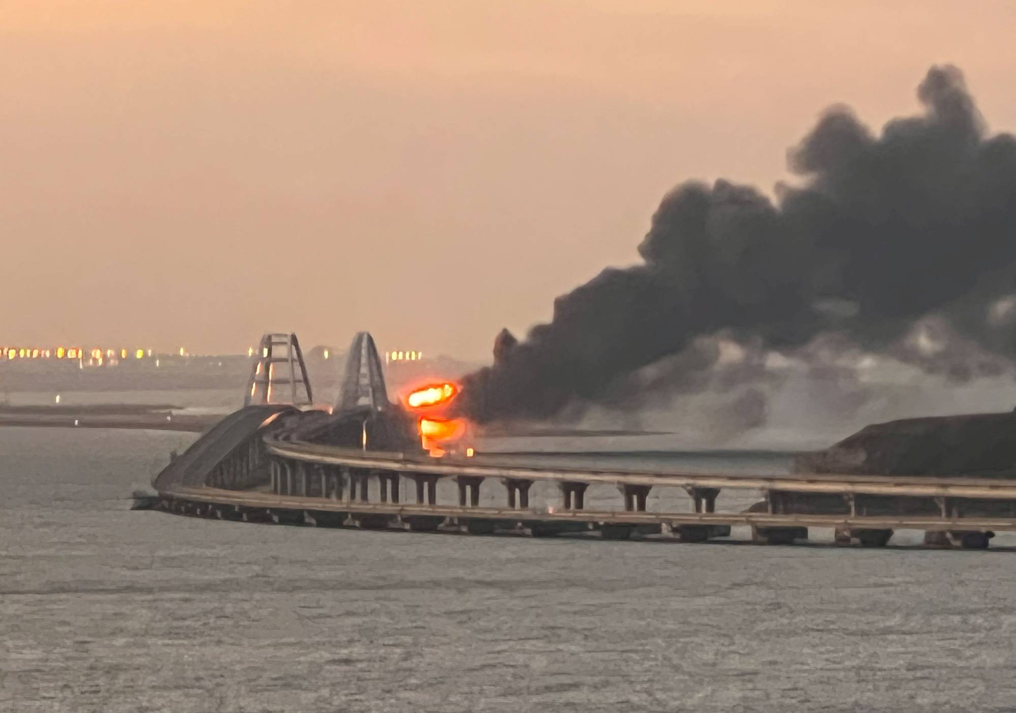 The Kerch Bridge, which links Russia with Crimea, is seen ablaze at sunrise in the Kerch Strait on Saturday. | REUTERS