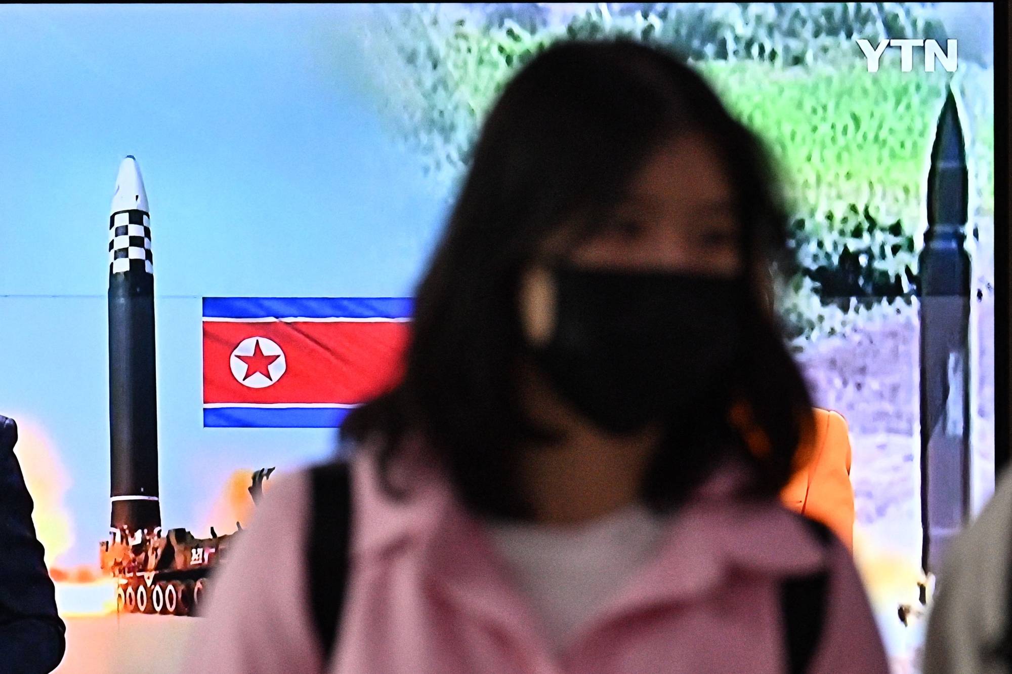 A woman at Seoul's main railway station, walks past a television news report about a North Korean missile test on Thursday. | AFP-JIJI
