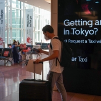 A passenger pushes luggage through the arrival lobby of Haneda Airport in Tokyo on Tuesday. Japan began accepting vaccinated visitors from 68 countries without visas Tuesday, ending almost three years of tighter border controls that kept tourists out of the nation. | BLOOMBERG