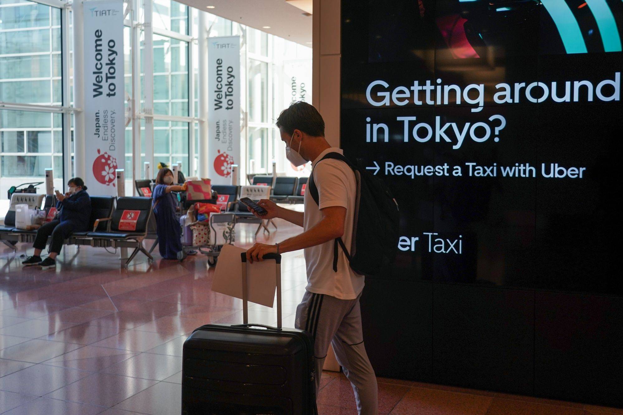 A passenger pushes luggage through the arrival lobby of Haneda Airport in Tokyo on Tuesday. Japan began accepting vaccinated visitors from 68 countries without visas Tuesday, ending almost three years of tighter border controls that kept tourists out of the nation. | Bloomberg