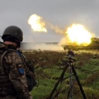 A Ukrainian soldier stands as a 2S1 Gvozdika self-propelled howitzer fires a shell on the front line in the Donetsk region on Monday. | AFP-JIJI
