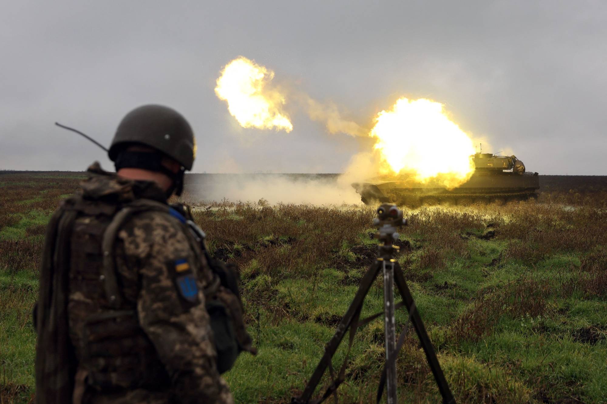 A Ukrainian soldier stands as a 2S1 Gvozdika self-propelled howitzer fires a shell on the front line in the Donetsk region on Monday. | AFP-JIJI