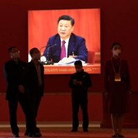 Visitors stand in front of a picture showing Chinese President Xi Jinping at the Beijing Exhibition Center in Beijing on Wednesday | AFP-JIJI
