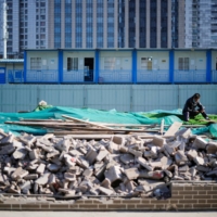 A worker rests on an unfinished road in Shanghai on Monday. Many economists say China\'s growth has relied too heavily on construction and investment. | REUTERS
