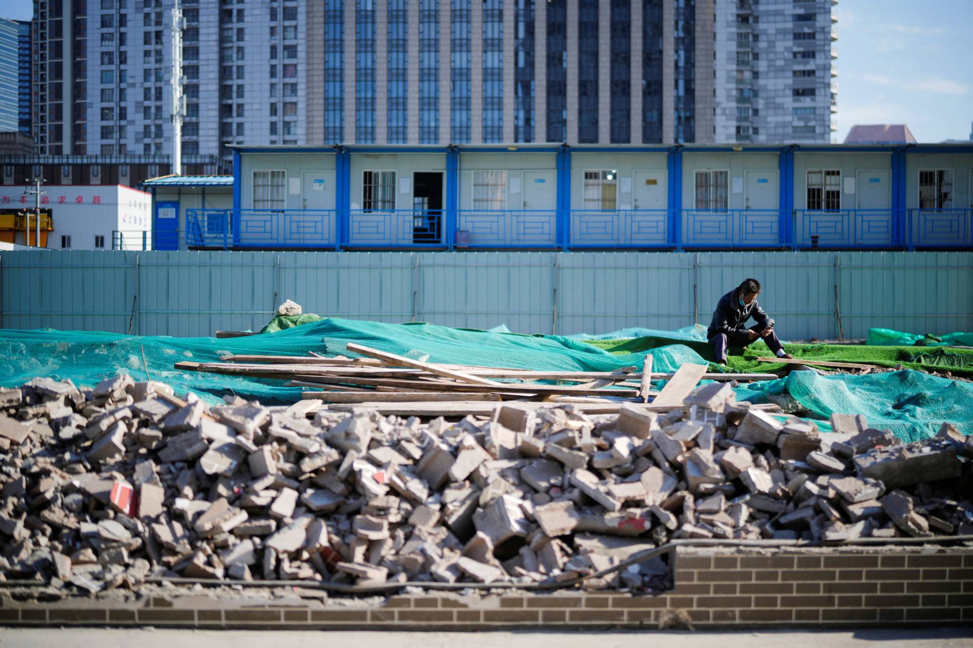 A worker rests on an unfinished road in Shanghai on Monday. Many economists say China's growth has relied too heavily on construction and investment. | REUTERS