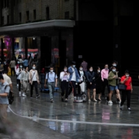 People wearing face masks walk on a street in Shanghai in September | REUTERS