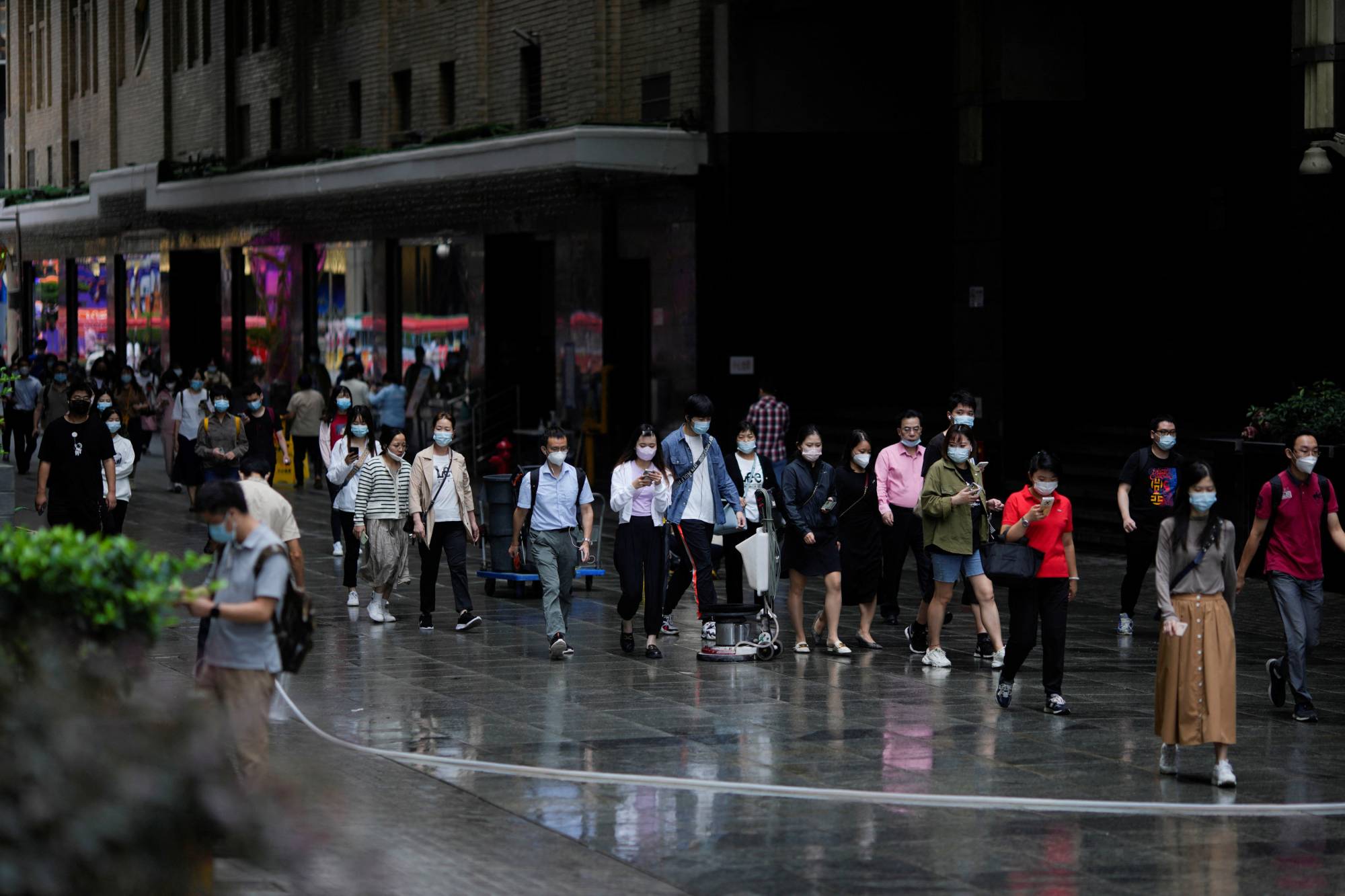 People wearing face masks walk on a street in Shanghai in September | REUTERS
