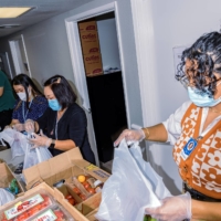Staff members from Centro La Familia, a neighborhood center in Fresno, sort donated food brought by Vue Vang to be distributed to people who need it. | ANDRI TAMBUNAN / THE NEW YORK TIMES