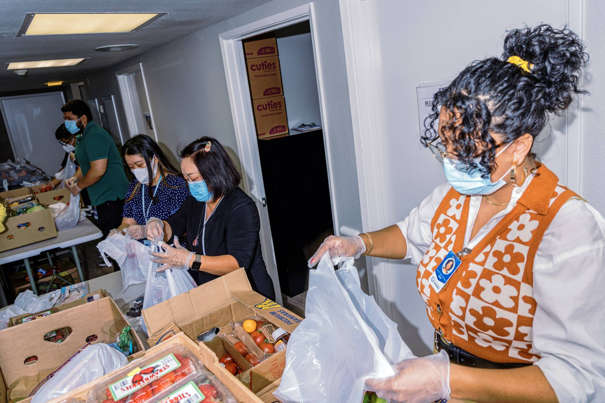 Staff members from Centro La Familia, a neighborhood center in Fresno, sort donated food brought by Vue Vang to be distributed to people who need it. | Andri Tambunan / The New York Times