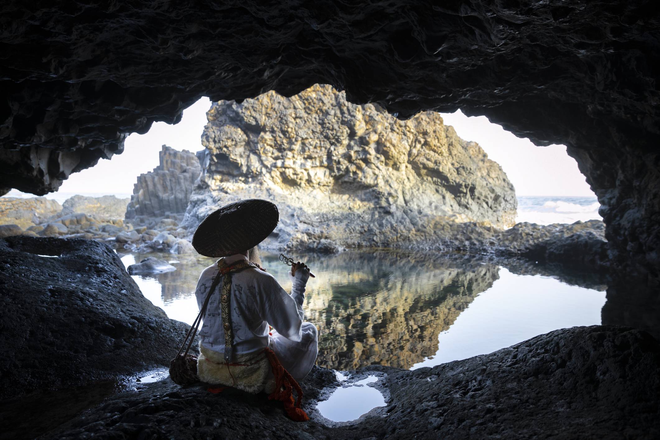 A monk dressed in typical pilgrimage garb sits in a cave for a meditation break. The white vestments have their origin in traditional funeral robes. | GETTY IMAGES