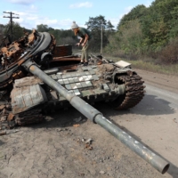 A girl inspects a destroyed Russian tank near the village of Oskol in Ukraine\'s Kharkiv region on Oct. 9.  | AFP-JIJI