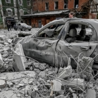 A woman stands near her car, which was destroyed by a Russian missile attack, in Zaporizhzhia, Ukraine, on Friday.   | REUTERS