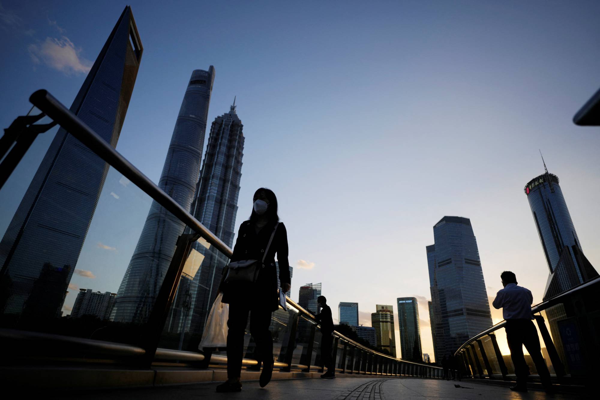 People walk on an overpass past office towers in the Lujiazui financial district of Shanghai on Monday. | REUTERS
