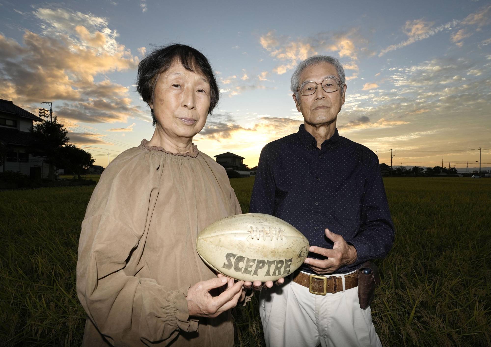 Mieko and Masaichi Hattori — mother and father of Yoshihiro Hattori, who was shot in 1992 in Louisiana — hold a rugby ball with a message written by their son's former classmate, on Oct. 14 in Nagoya. | KYODO