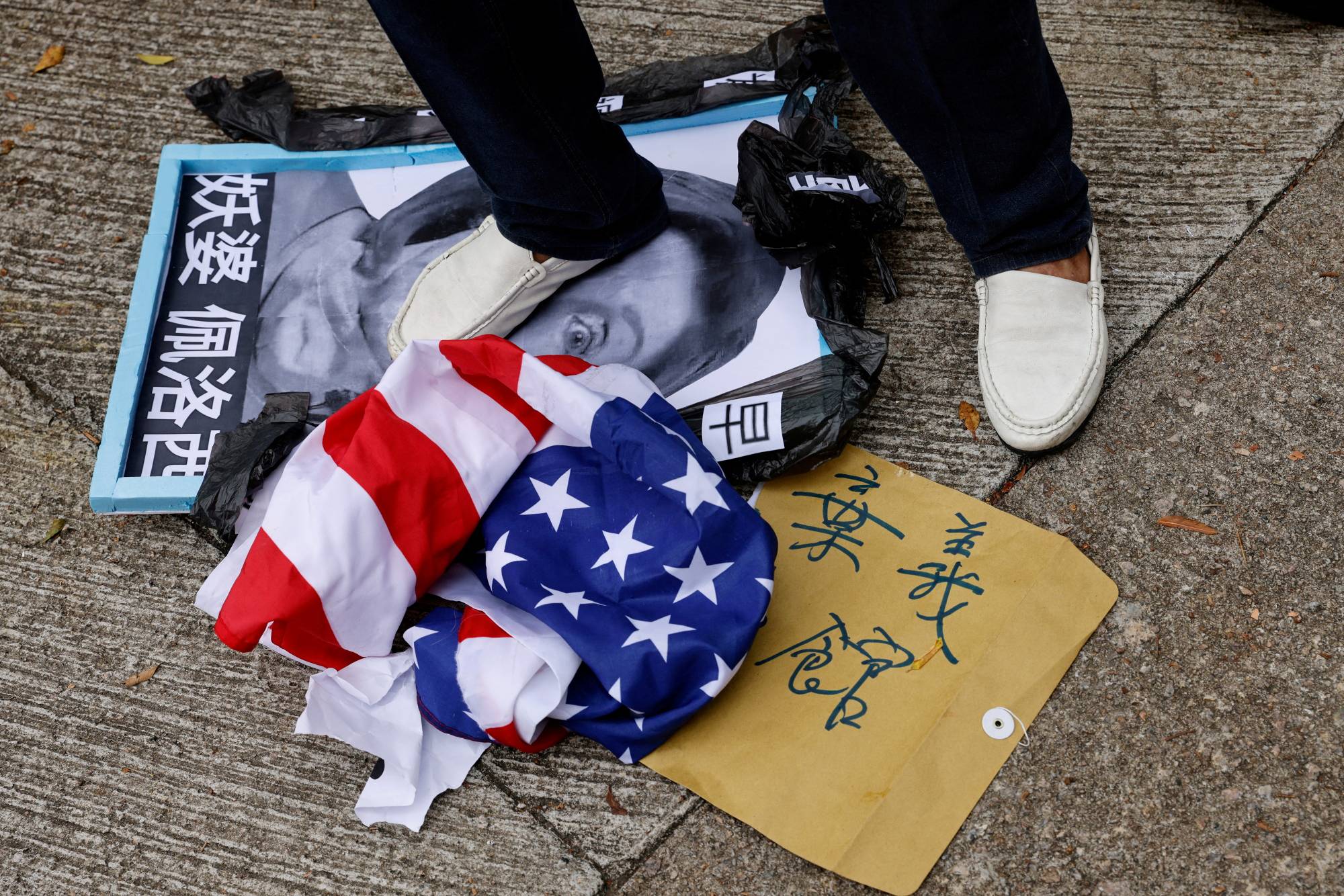A pro-China supporter steps on a defaced photo of U.S. House of Representatives Speaker Nancy Pelosi during a protest against her visit to Taiwan, outside the Consulate General of the United States in Hong Kong on Aug. 3. | REUTERS