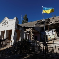 A Ukrainian national flag rises over a local council\'s headquarter building, heavily damaged during Russia\'s attack in the village of Lymany near a frontline in Mykolaiv region, Ukraine, on Tuesday | REUTERS