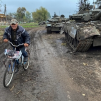 A local resident rides past abandoned Russian tanks in the village of Kurylivka, in the Kharkiv region of Ukraine, on Oct. 1.    | REUTERS