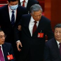 Former Chinese President Hu Jintao is led out of his seat next to Chinese leader Xi Jinping and Premier Li Keqiang, during the closing ceremony of a twice-a-decade Communist Party congress at Beijing\'s Great Hall of the People on Saturday. | REUTERS