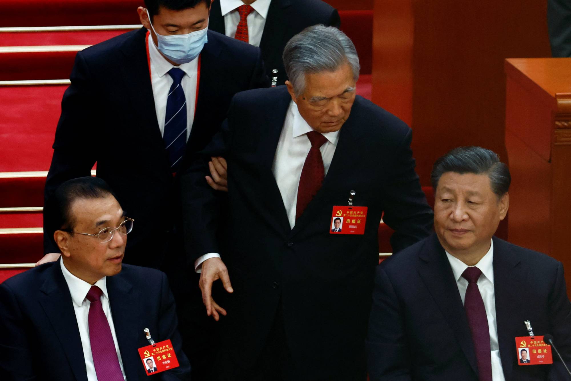 Former Chinese President Hu Jintao is led out of his seat next to Chinese leader Xi Jinping and Premier Li Keqiang, during the closing ceremony of a twice-a-decade Communist Party congress at Beijing's Great Hall of the People on Saturday. | REUTERS