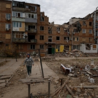 A resident walks Saturday in front of her apartment building, which was heavily damaged by a recent Russian missile attack in Mykolaiv, Ukraine. | REUTERS