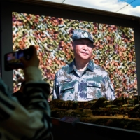 A visitor takes pictures near models of military equipment and a giant screen displaying Chinese leader Xi Jinping at the Military Museum in Beijing on Oct. 8. | REUTERS