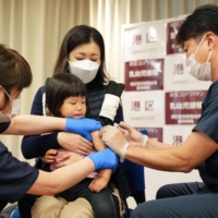 A child receives a dose of COVID-19 vaccine at a hospital in Tokyo on Tuesday. | KYODO
