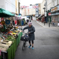 A customer views produce at a market stall on Portobello Road in London. | REUTERS