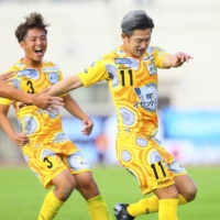 Suzuka PG forward Kazuyoshi Miura (right) celebrates after scoring a penalty kick against Tiamo Hirakata in the fourth-division JFL in Hirakata, Osaka Prefecture, on Sunday. | SUZUKA POINT GETTERS / VIA KYODO