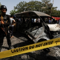 A police officer stands guard near a passenger van after a blast at the entrance of the Confucius Institute at University of Karachi, Pakistan, in April. | REUTERS