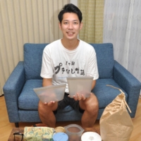 Tomoyuki Hirose, who tried a month without plastics, holds silicone containers he used during the project. | NISHINIPPON SHIMBUN
