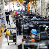 Employees work on the Mitsubishi Fuso Truck and Bus assembly line in Kawasaki in May 2020. According to an estimate by consulting firm Arthur D. Little, about 680,000 people work for auto parts suppliers, but the electric vehicle shift could see about 84,000 jobs cut by 2050. | REUTERS