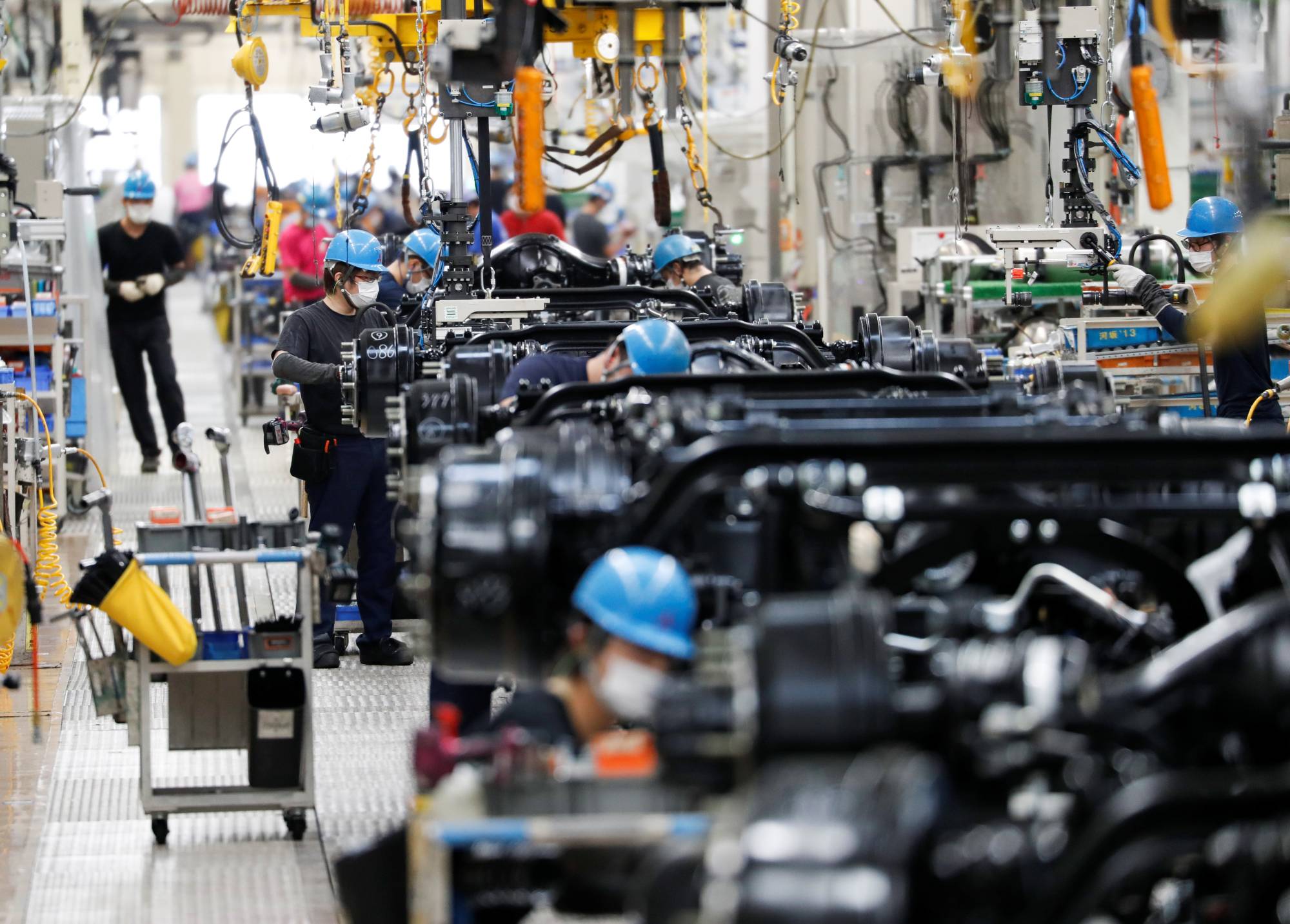 Employees work on the Mitsubishi Fuso Truck and Bus assembly line in Kawasaki in May 2020. According to an estimate by consulting firm Arthur D. Little, about 680,000 people work for auto parts suppliers, but the electric vehicle shift could see about 84,000 jobs cut by 2050. | REUTERS