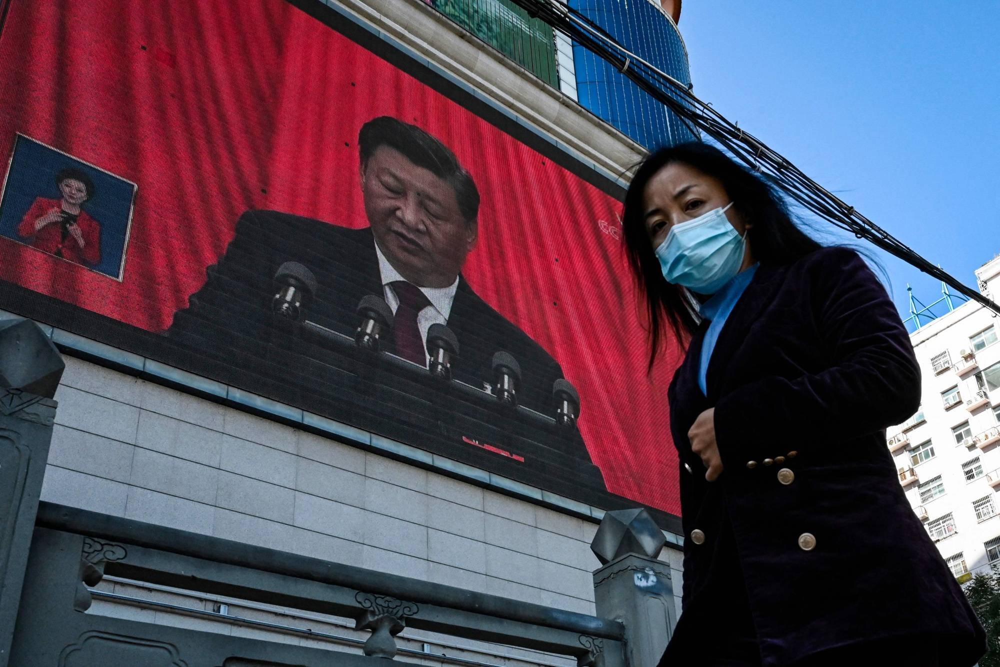 An outdoor screen displays a live speech of Chinese leader Xi Jinping from Beijing during the opening session of a rare Chinese Communist Party congress, as a pedestrian walks past in Yan'an, China, on Oct. 16. | AFP-JIJI