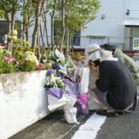 A woman lays flowers Saturday in the city of Kyoto near the site where Gyoza no Ohsho President Takayuki Ohigashi was fatally shot in 2013. | KYODO