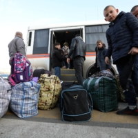 Civilians evacuated from the Russian-controlled Kherson region of Ukraine get off a bus as they arrive at a local railway station, after Russian-installed officials extended an evacuation order to the area along the eastern bank of the Dnipro River, in the town of Dzhankoi, Crimea, on Wednesday.  | REUTERS/