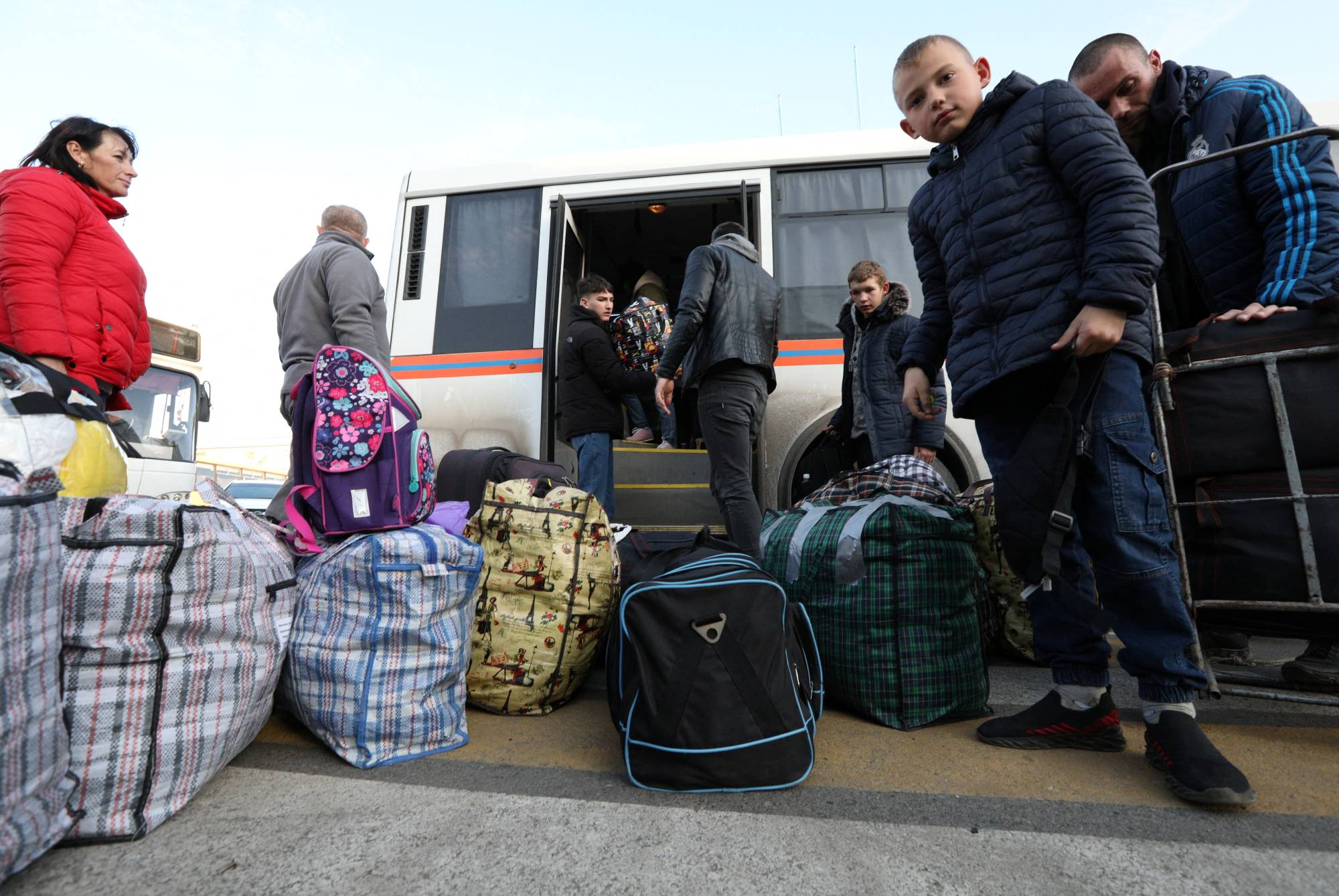 Civilians evacuated from the Russian-controlled Kherson region of Ukraine get off a bus as they arrive at a local railway station, after Russian-installed officials extended an evacuation order to the area along the eastern bank of the Dnipro River, in the town of Dzhankoi, Crimea, on Wednesday.  | REUTERS