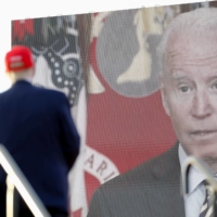 A video of U.S. President Joe Biden is seen on a screen as former President Donald Trump speaks during a rally ahead of the midterm congressional elections, in Miami on Sunday. | REUTERS