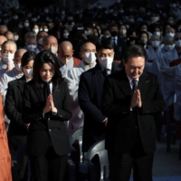 South Korean President Yoon Suk-yeol and his wife, Kim Keon-hee, attend a Buddhist ceremony commemorating victims of a crowd crush that happened during Halloween festivities, at Chogye Buddhist temple in Seoul on Friday. | YONHAP / VIA REUTERS 