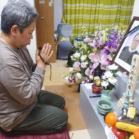 Eiji Iioka prays on Friday for his wife, Ayano, who died shortly after receiving a COVID-19 shot, in Aisai, Aichi Prefecture. | KYODO