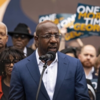 Democratic Sen. Raphael Warnock speaks by a mural of John Lewis in Atlanta on Thursday as Georgia\'s Senate election headed to a runoff contest.  | NICOLE CRAINE / THE NEW YORK TIMES