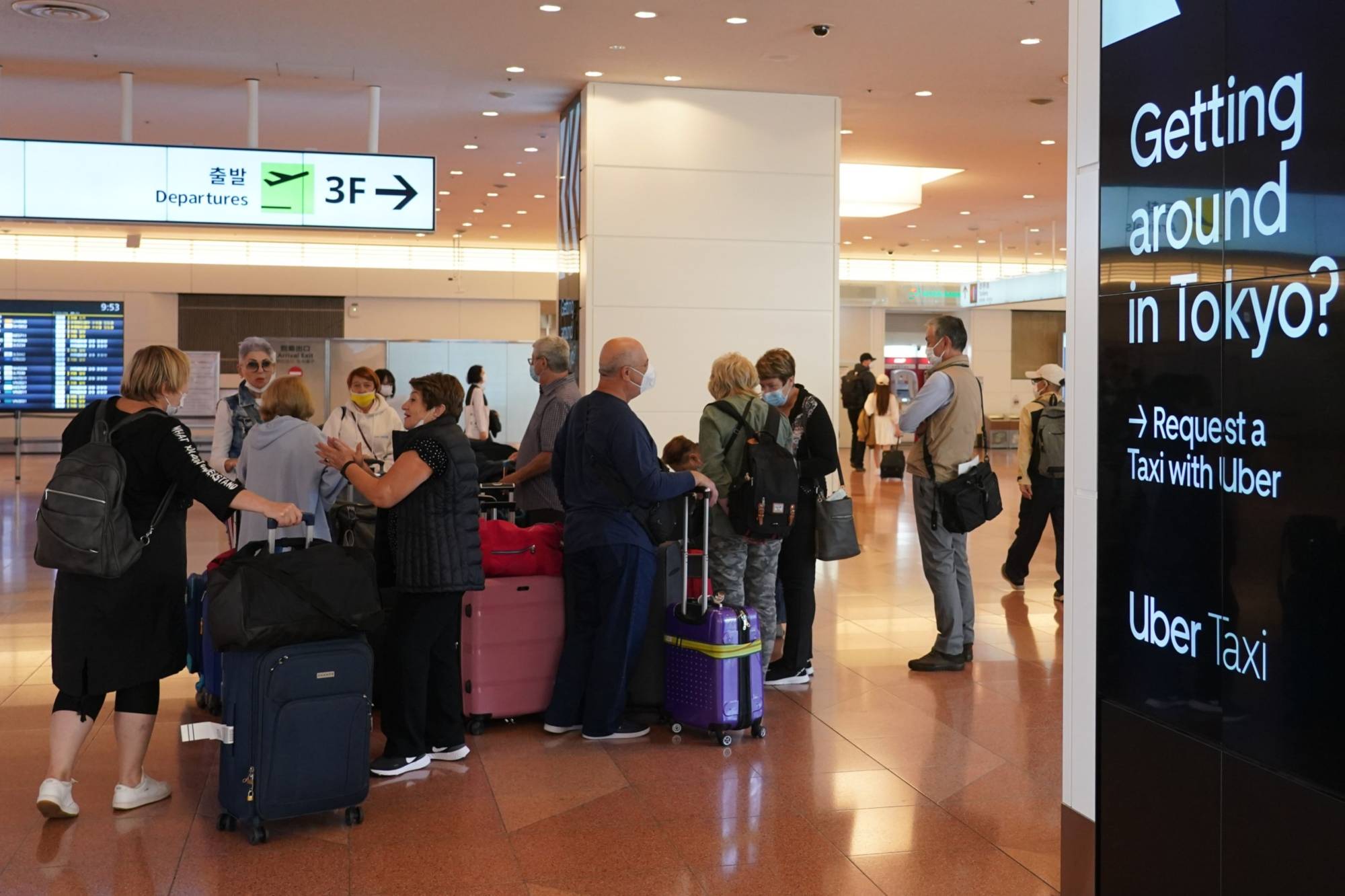 Passengers with luggage gather at the arrival lobby of Haneda Airport in Tokyo on Oct. 11. | BLOOMBERG