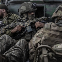 Members of the Ukrainian Armed Forces ride in the back of a vehicle in the southern Ukrainian city of Kherson on Wednesday. | FINBARR O\'REILLY / THE NEW YORK TIMES