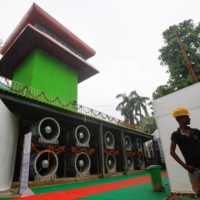 A worker stands next to a newly installed \"smog tower,\" a 20-meter-tall air-purifier, in New Delhi. | REUTERS
