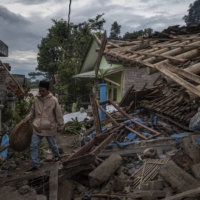 Muhammad Azid sifts through the wreckage of his home following a landslide triggered by an earthquake, in Cianjur on Wednesday.  | ULET IFANSASTI / THE NEW YORK TIMES
