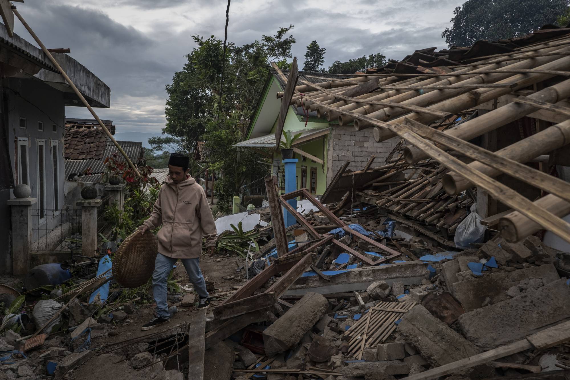 Muhammad Azid sifts through the wreckage of his home following a landslide triggered by an earthquake, in Cianjur on Wednesday. | Ulet Ifansasti / The New York Times