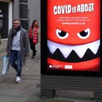People walk past an advertisement warning about COVID-19 in Manchester, England, on Saturday. | REUTERS