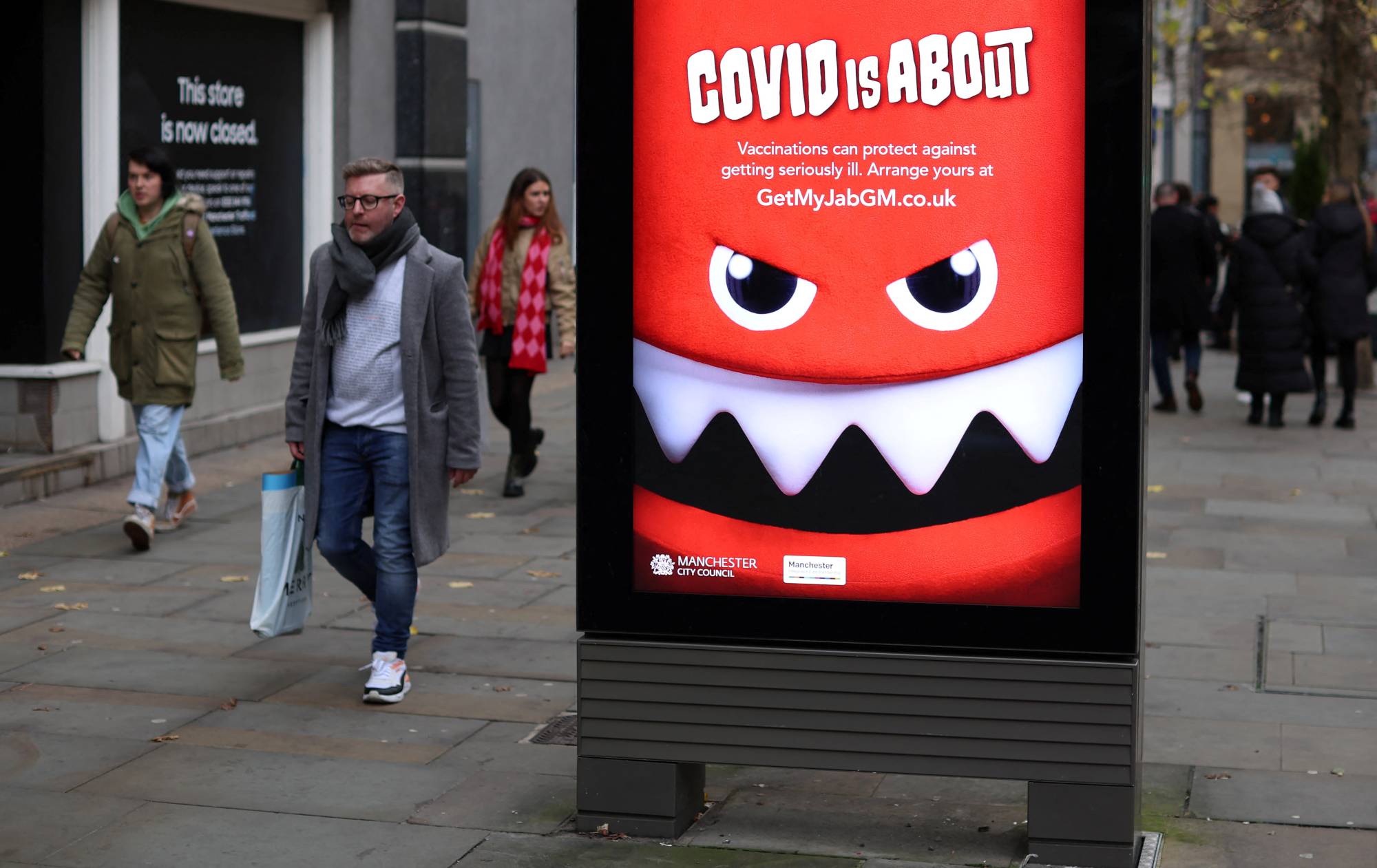 People walk past an advertisement warning about COVID-19 in Manchester, England, on Saturday. | REUTERS
