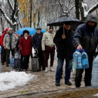 Residents stand in line to fill up bottles with fresh drinking water after critical civil infrastructure was hit by Russian missile attacks in Kyiv on Thursday. | REUTERS