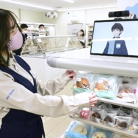 An avatar recommends products at a new Green Lawson store in Tokyo’s Toshima Ward on Monday. Lawson has opened its first convenience store staffed by on-screen avatars remotely controlled by employees. | KYODO