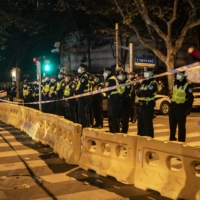 Police officers block a street where protests had taken place the night before, in Shanghai on Sunday.   | THE NEW YORK TIMES